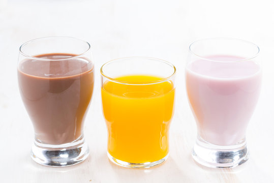 orange juice, chocolate milk and fruit yoghurt on white table