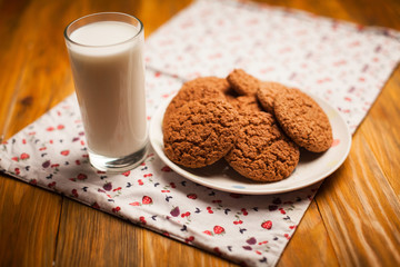 Oatmeal cookies and glass of milk on napkin on table