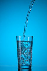 water pouring into glass on blue