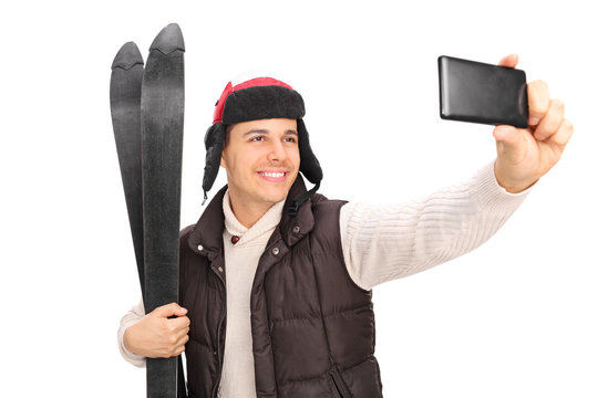Young guy taking a selfie with his skis
