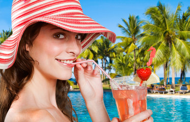 Junge Frau mit Cocktail am Hotelpool