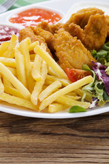Nuggets and chips on a plate served with dip and salads