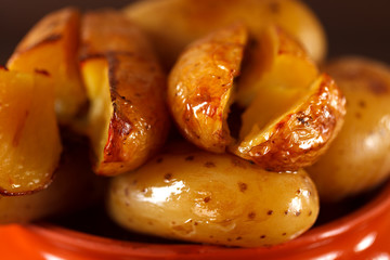 Baked potato in a clay pot on a background of the dark wooden 