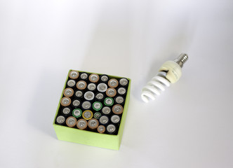 Used rechargeable batteries and and economic bulb on white backg