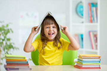 Student kid with a book over her head