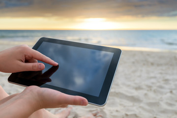 Woman holding a tablet at the beach during a warm sunset