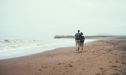 Traveler loving couple walking on beach near the sea