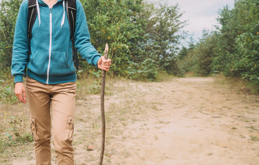 Hiker woman walking with a wooden stick in forest
