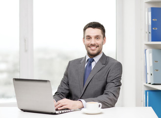 Fototapeta premium smiling businessman with laptop and coffee