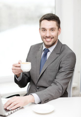 smiling businessman with laptop and coffee