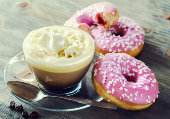 Cup of coffee with pink glazed donuts on wooden background vinta