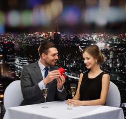 excited young woman looking at boyfriend with box