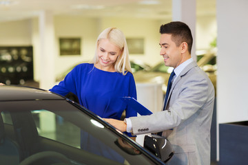 happy woman with car dealer in auto show or salon