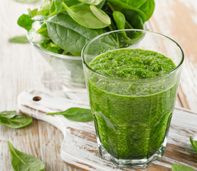 spinach smoothie in a glass on  wooden background