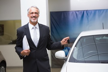 Smiling businessman holding car key and folder