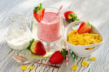 Healthy morning meal with cornflakes, strawberry smoothie and be