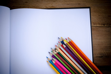 Fototapeta premium Color pencil and sketchbook on wooden background