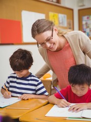Pretty teacher helping pupil in classroom