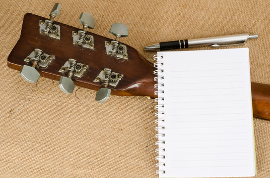 blank paper with pen on old acoustic guitar