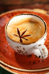 A cup of coffee with cinnamon sticks  on wood