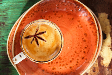 A cup of coffee with cinnamon sticks  on wood