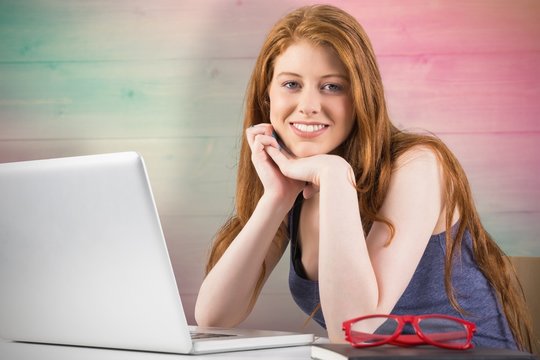 Composite image of pretty redhead working on laptop