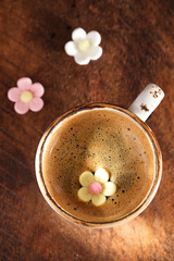 A cup of espresso coffee with sugar flowers, rustic style