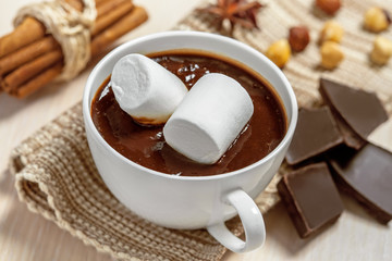 Hot chocolate with marshmallows, cinnamon and nuts on table