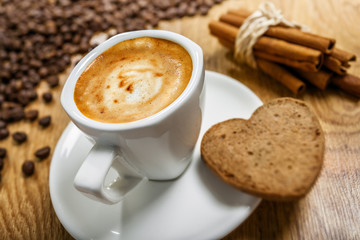 Cup of coffee with cookie heart and cinnamon