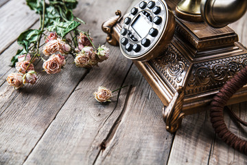 Old vintage black rotary phone and a bouquet of roses