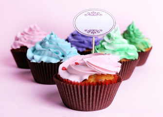 Delicious cupcakes with inscription on color background