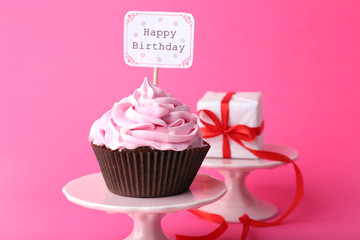 Delicious cupcake with inscription on pink background