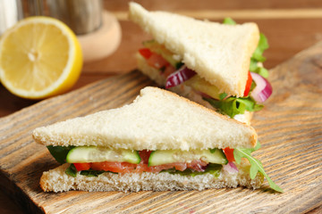 Club sandwich with salmon on wooden background