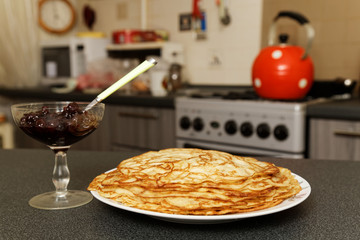Pancakes and jam on the background of the kitchen