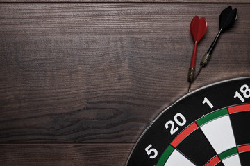 target and two darts over brown wooden table background