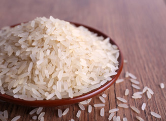 Grain of rice on plate on wooden background