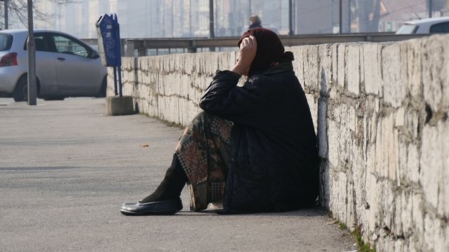 A woman begs on the street.
