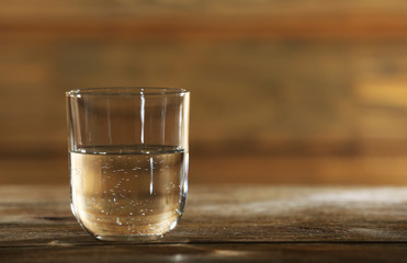 Glass of clean mineral water on rustic wooden background