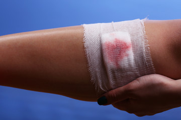 Wounded leg with bandage on blue background