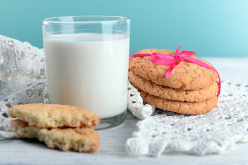 Tasty cookies and glass of milk on color wooden background