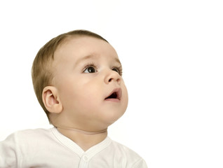 Cute baby boy looking up surprised.Baby in white looking curious