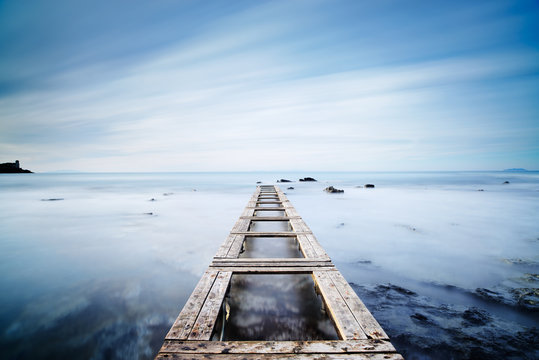 Fototapeta Wooden pier or jetty on a blue ocean in the morning.Long Exposur