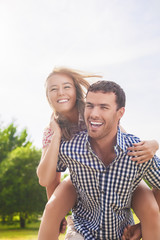 Happy and Cheerful Young Caucasian Couple Piggybacking Outdoors