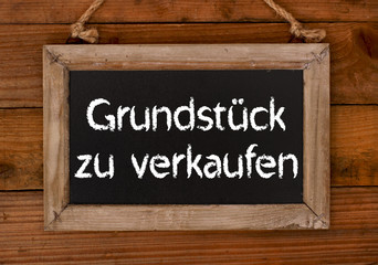 Grundst&uuml;ck zu verkaufen / Schild mit Holzhintergrund