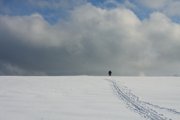 Man and woman on ski track against cloudy sky