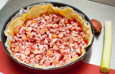 pizza with vegetables and sausages in process of preparation