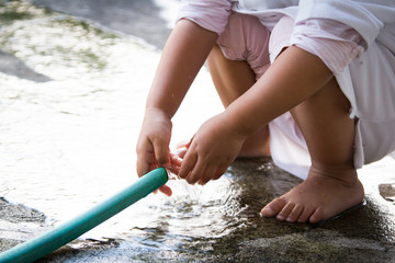 Cute little girl is washing her hand with rubber tube