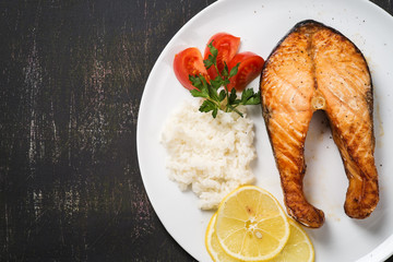 Top view of baked trout with vegetables and rice. Space for text