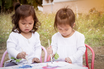 Cute little girls are painting with watercolor together in soft