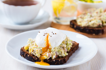 Avocado and feta smash on rye bread and poached  egg on top
